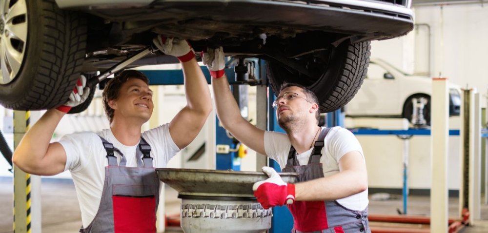 automobilu na servisní rampě s mechanikem měnícím olej